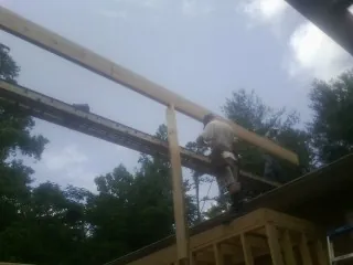 Carpenter setting a ridge beam over a new addition frame — Ice Dam Removal by Roofing Brothers in De Graff