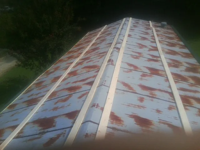 Rusted metal roof panels with new wood purlins before replacement — Storm Damage Roof Repair in De Graff by Roofing Brothers