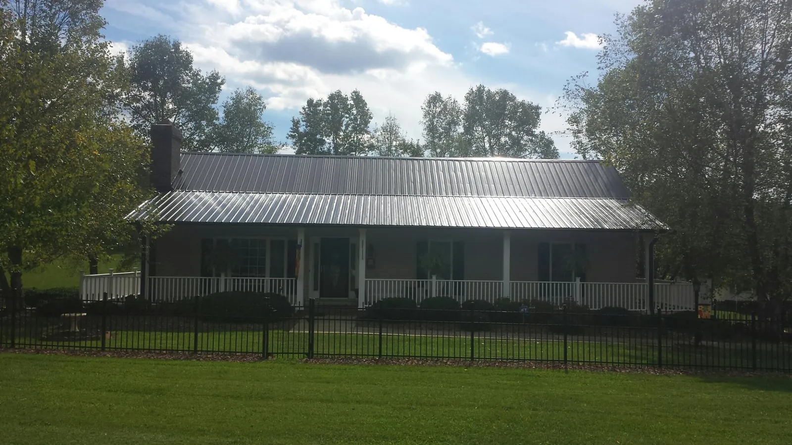 Gray metal roof on a brick ranch with a full width front porch — Gutter Guard Installation work by our crew in De Graff