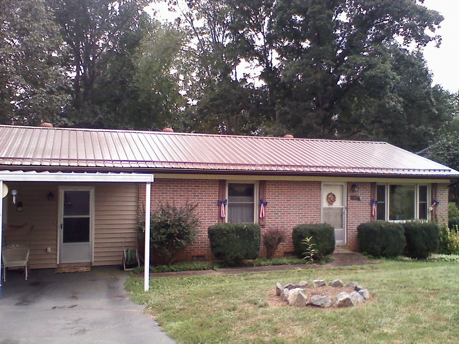 Bronze metal roof and carport on a brick ranch home — Roof Repair work by our crew in De Graff